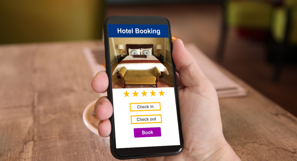 5 Latest Trends in Hospitality Industry man holding mobile phone in hand to make a hotel booking and checkin